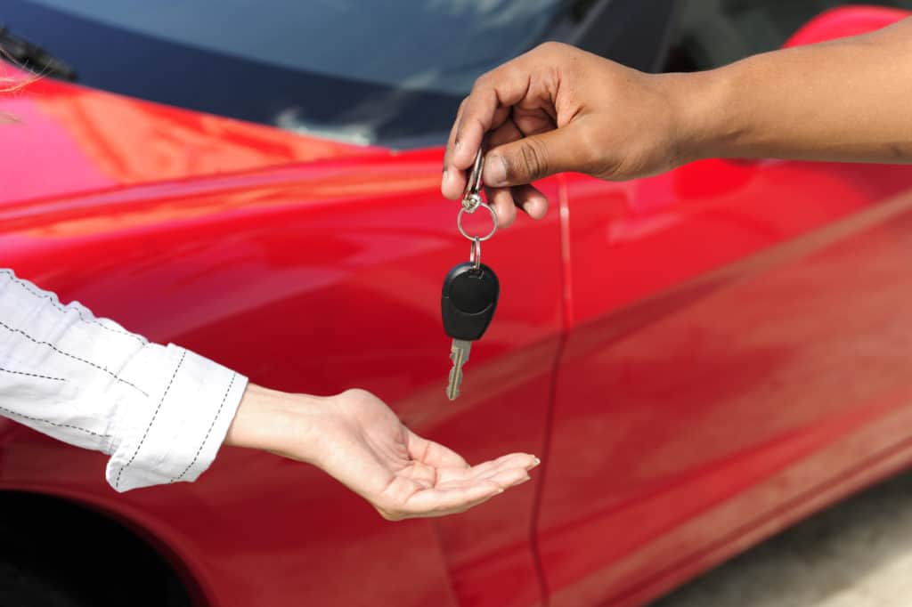 car dealership: woman receiving car key from salesman